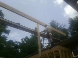 Carpenter setting a ridge beam over a new addition frame — Ice Dam Removal by Roofing Brothers in Milton