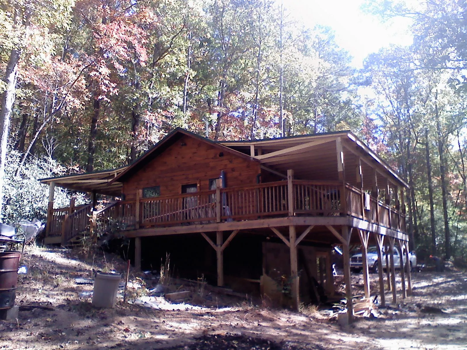 Log cabin with a wraparound porch and metal roof in the fall in Milton
